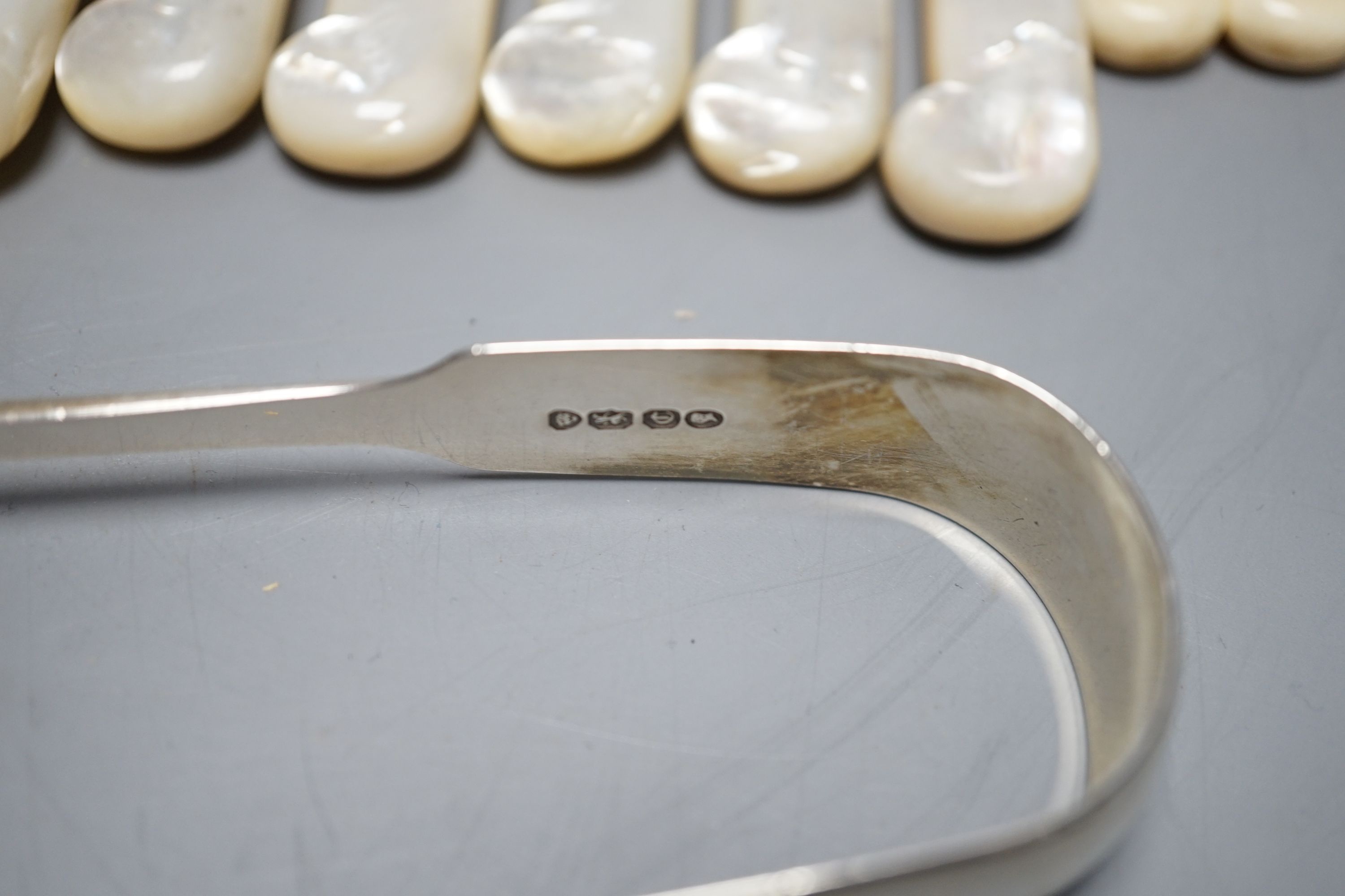 Six pairs of George V mother of pearl handled silver dessert eaters, George Howson, Sheffield, 1921, a pair of silver sugar tongs and assorted plated flatware.
